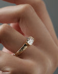 Close-up side view of the Magnolia half bezel solitaire on a woman's finger, highlighting the hand engraved magnolia flowers and detailed diamond setting.