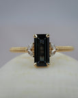 Millie cluster solitaire engagement featuring a rectangular lintel sapphire, marquise diamonds, and a migraines beaded gold band.