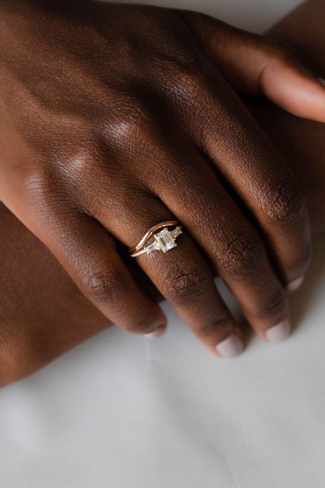 Model wearing the Three Stone Adele Solitaire Engagement Ring in yellow gold by Fluid Jewellery