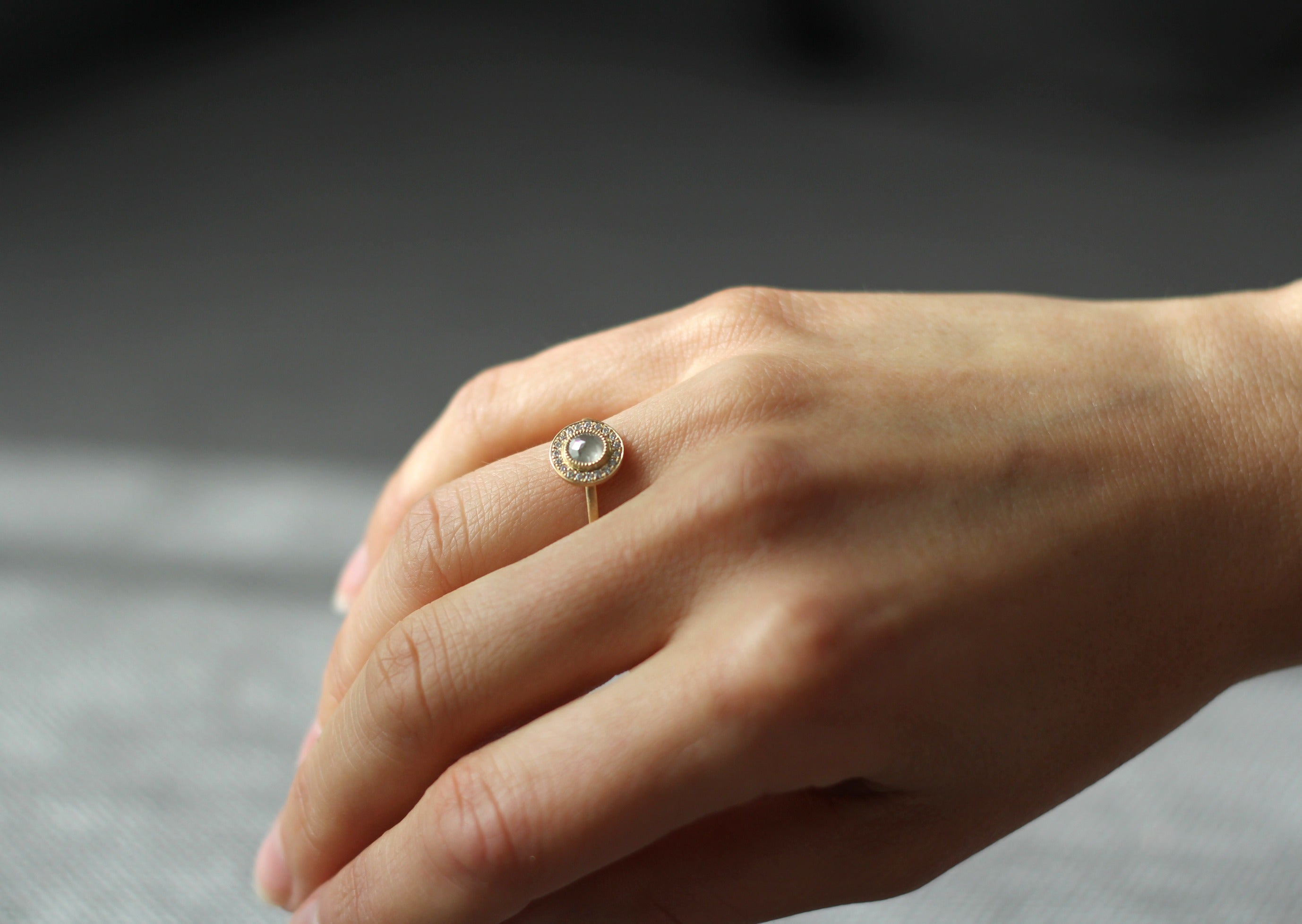 Model wearing the Halo Aura Solitaire Engagement Ring in yellow gold by Fluid Jewellery