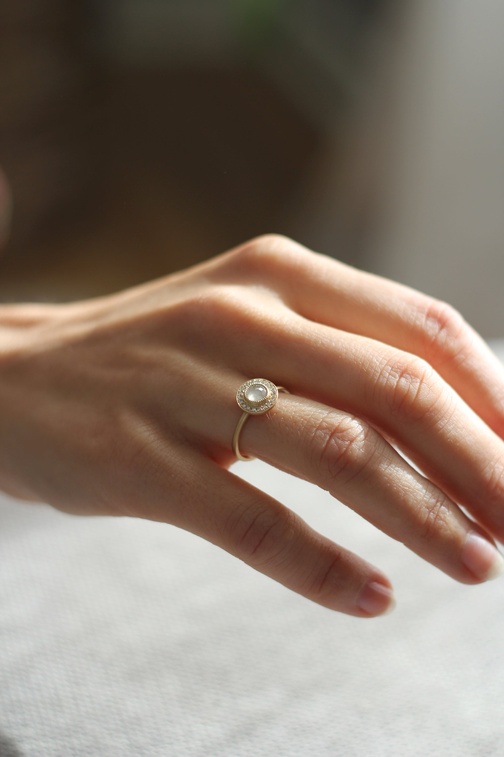 Model wearing the Halo Aura Solitaire Engagement Ring in yellow gold by Fluid Jewellery 3