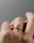Close-up of a woman's hand wearing the Aura halo solitaire with a champagne toned Australian salt and pepper oval shaped rose cut diamond surrounded by Canadian diamonds. 