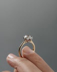Close-up of the side of the Cala tulip-style cathedral solitaire held between a woman's fingers, showing the antique floral filigree inspired platinum and gold setting. 