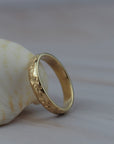 Close-up detail of hand engraved poppy flowers on a Fairmined yellow gold band.