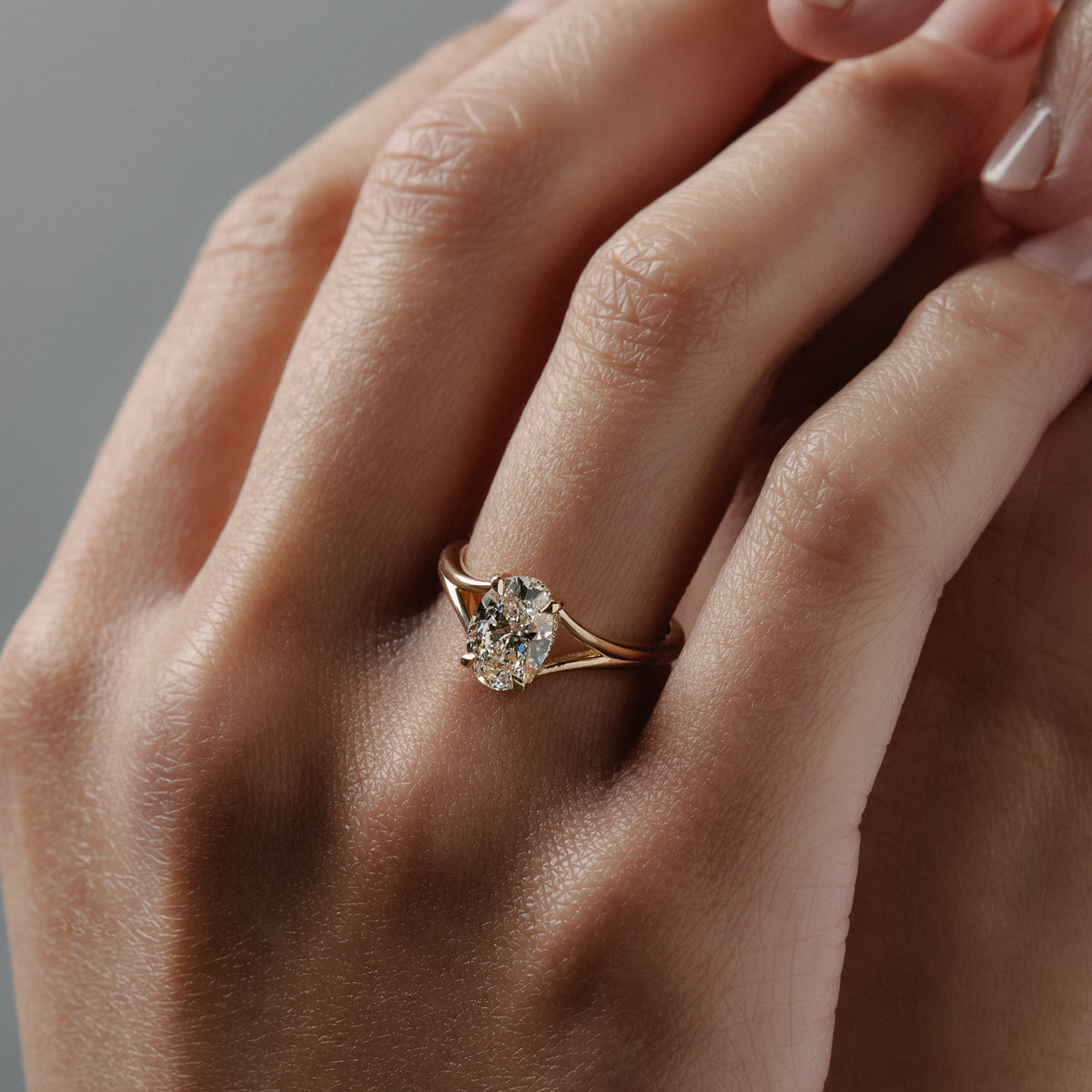 Love Knot split shank diamond solitaire engagement ring featuring a hidden halo and intertwined gold setting on hand.