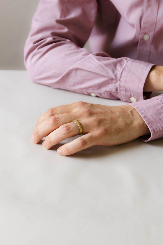 Close up of model hand wearing the mens Arena wedding band in yellow gold 2