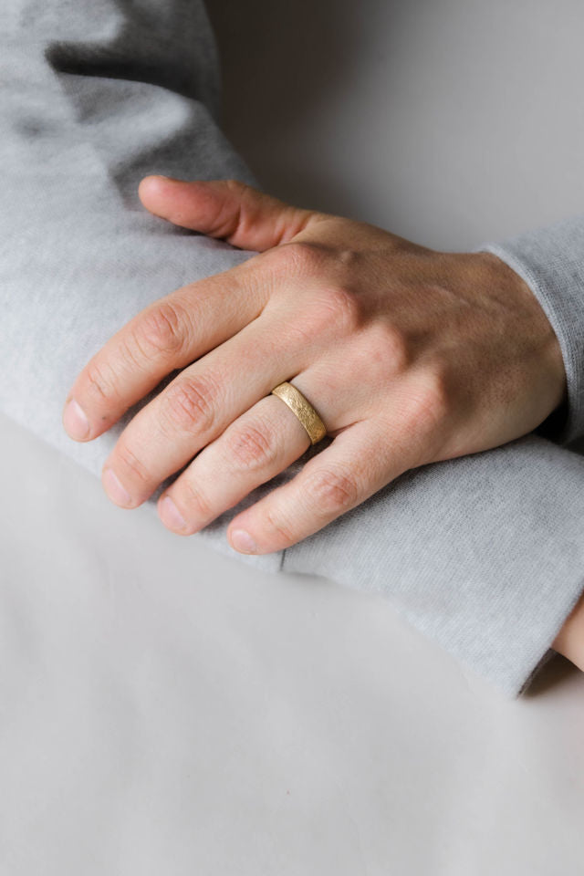 Close up of model hand wearing the mens Arena wedding band in yellow gold
