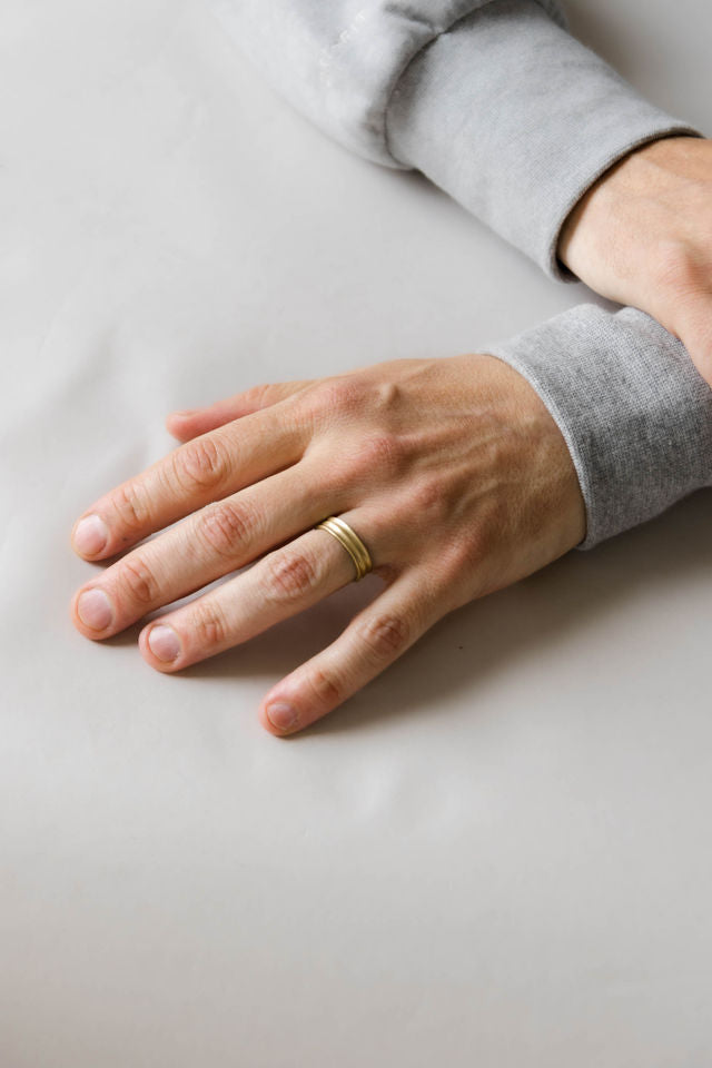 Close up of model ahnd wearing the mens Groove wedding band in yellow gold 2