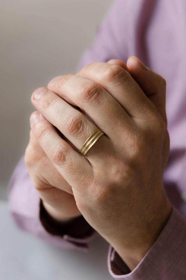 Close up of model ahnd wearing the mens Groove wedding band in yellow gold