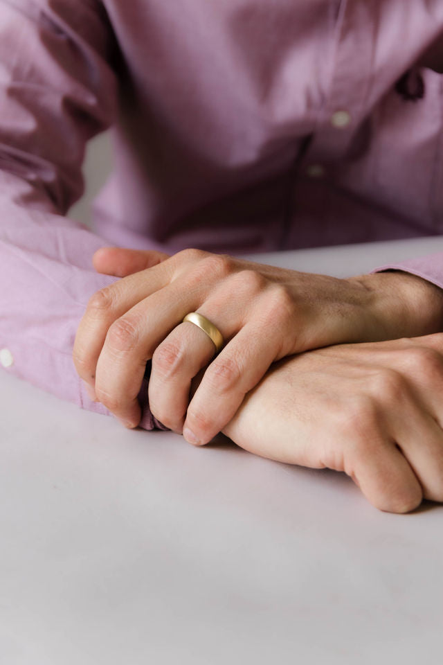 Close up of model hand wearing the mens Half Round wedding band in gold