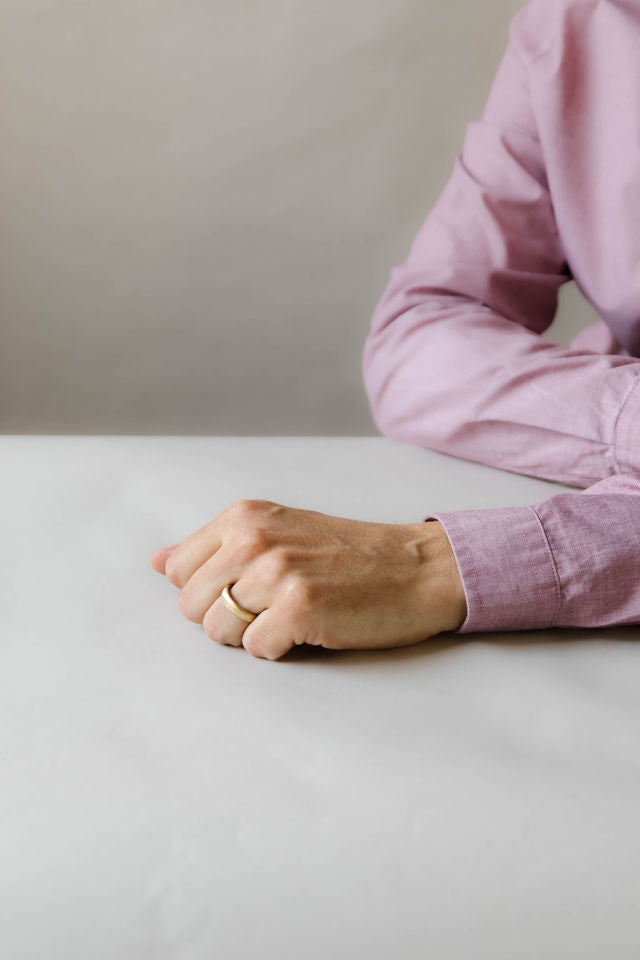 Close up of model hand wearing the mens Organic wedding band in gold 2
