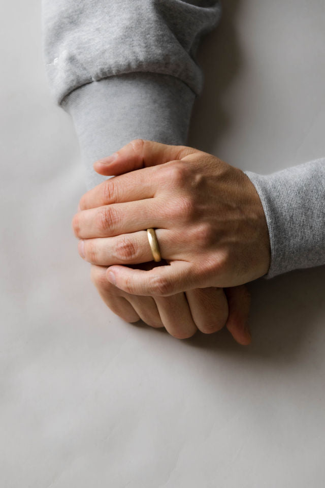 Close up of model hand wearing the mens Organic wedding band in gold