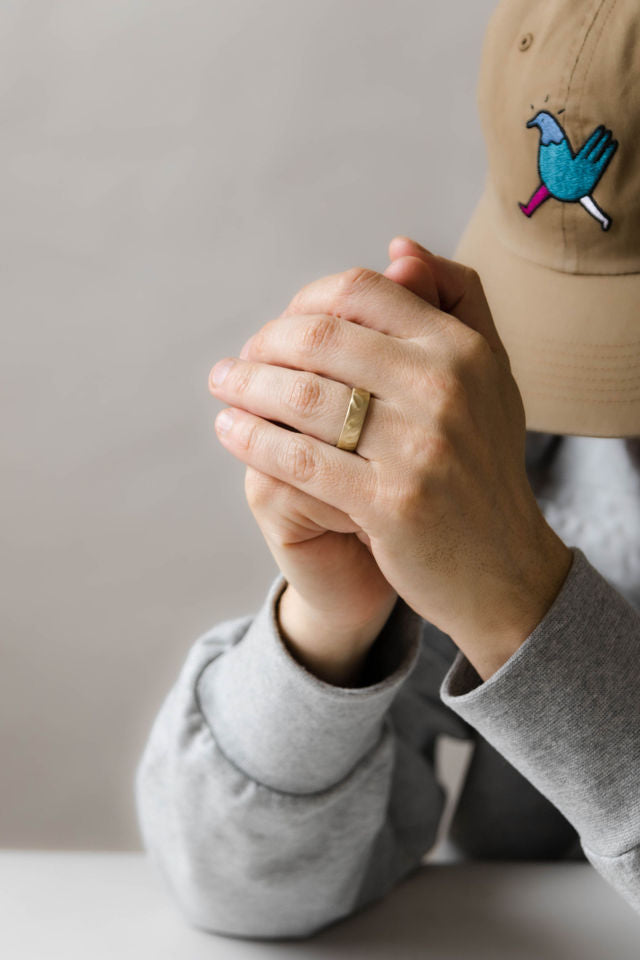 Close up of model hand wearing the mens Wave wedding band in yellow gold 2