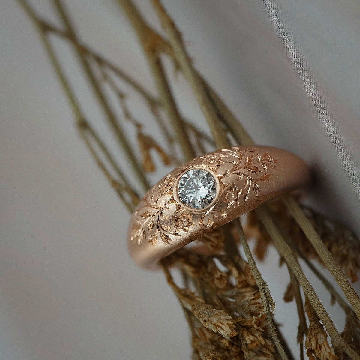 Close-up of the hand engraved floral details on the side of the Mrs. Erykah Fairmined gold engagement ring.
