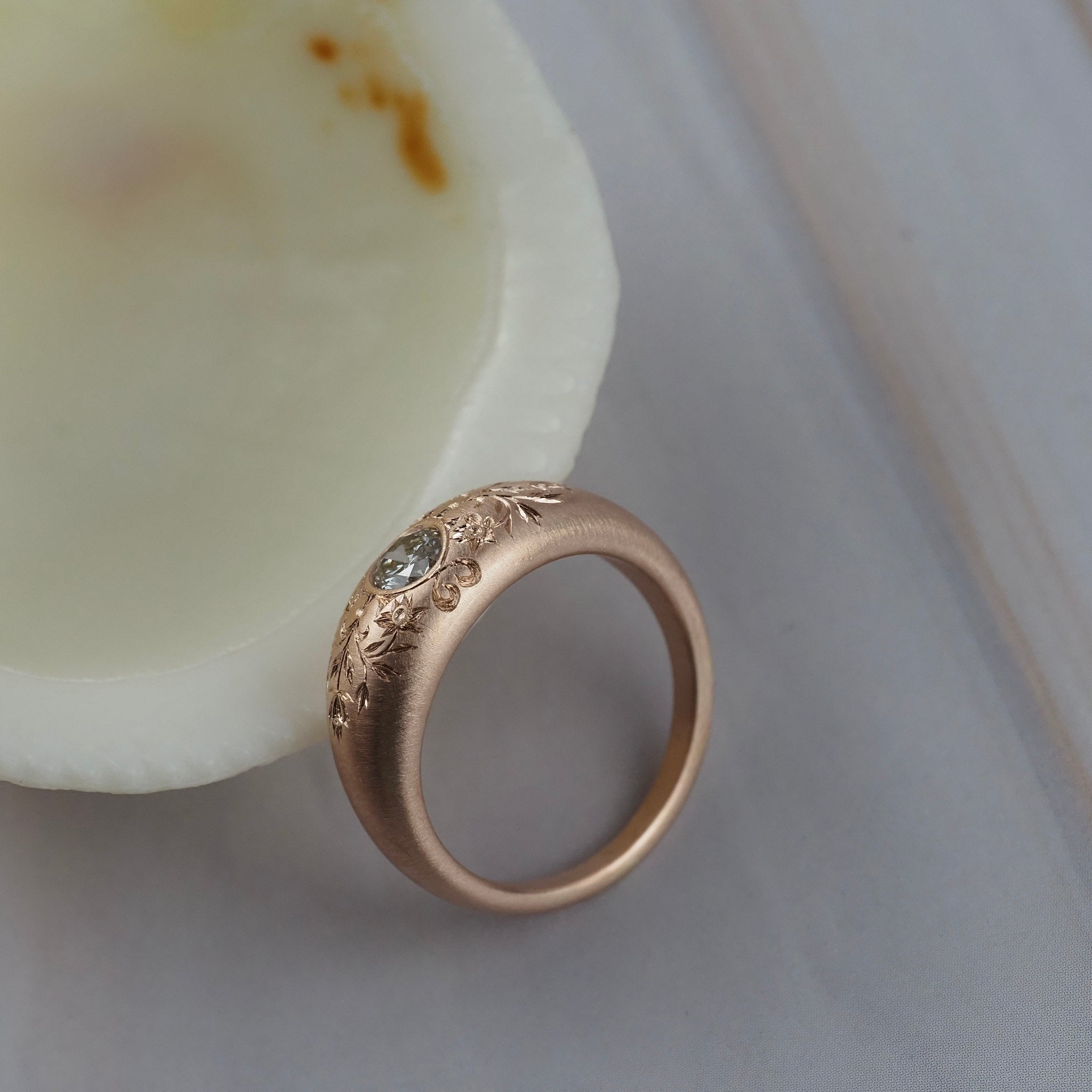 Close-up of the hand engraved floral details on the side of the Mrs. Erykah Fairmined gold engagement ring.