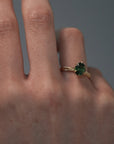 Close-up video of a woman wearing the Fern hand engraved solitaire in Fairmined gold, showcasing the step-cut oval green sapphire and detailed gold band.