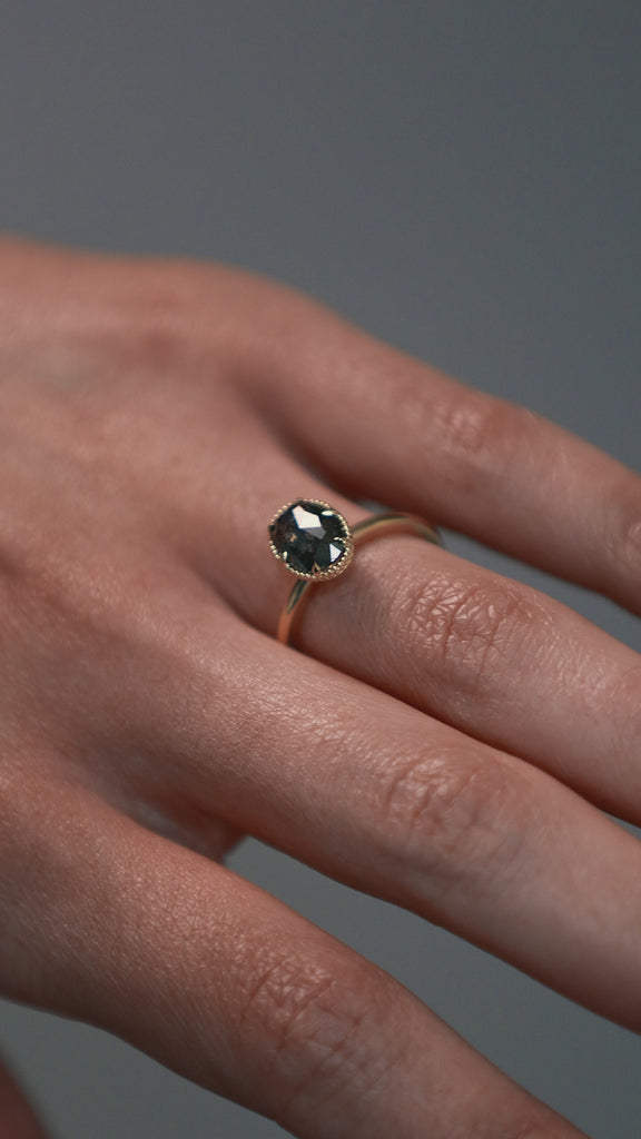 Close-up video of a woman wearing the Elanor salt and pepper oval diamond six-claw solitaire, showing the Art Deco woven setting and milgrain edge. 