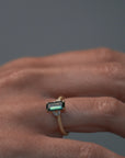 Close-up video of the Millie cluster solitaire engagement ring worn on a woman's hand, showcasing the rectangular teal sapphire, marquise diamonds, and milgrained beaded band.