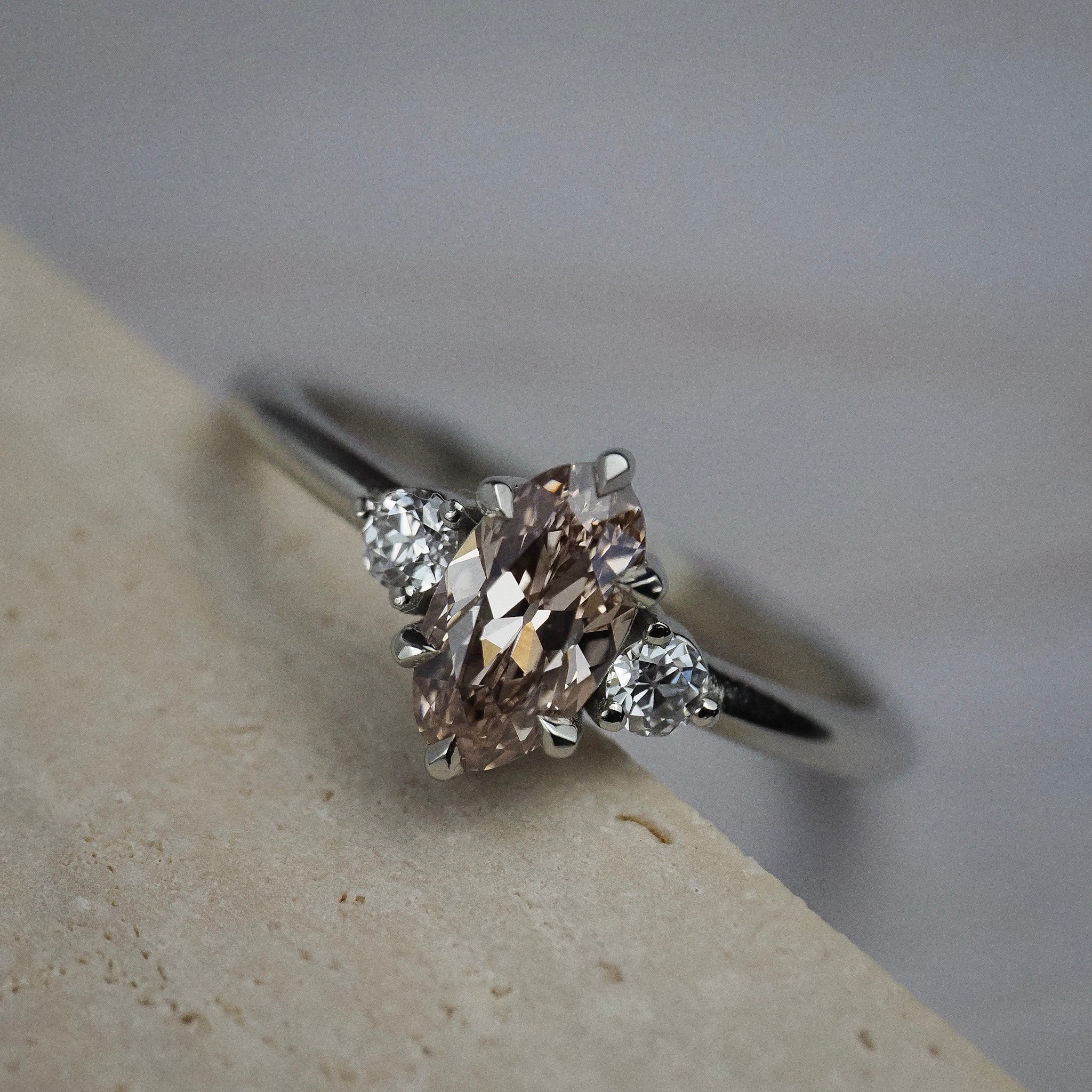 Rebecca three stone engagement ring featuring a champagne  toned moval cut diamond accented by white full cut diamonds.