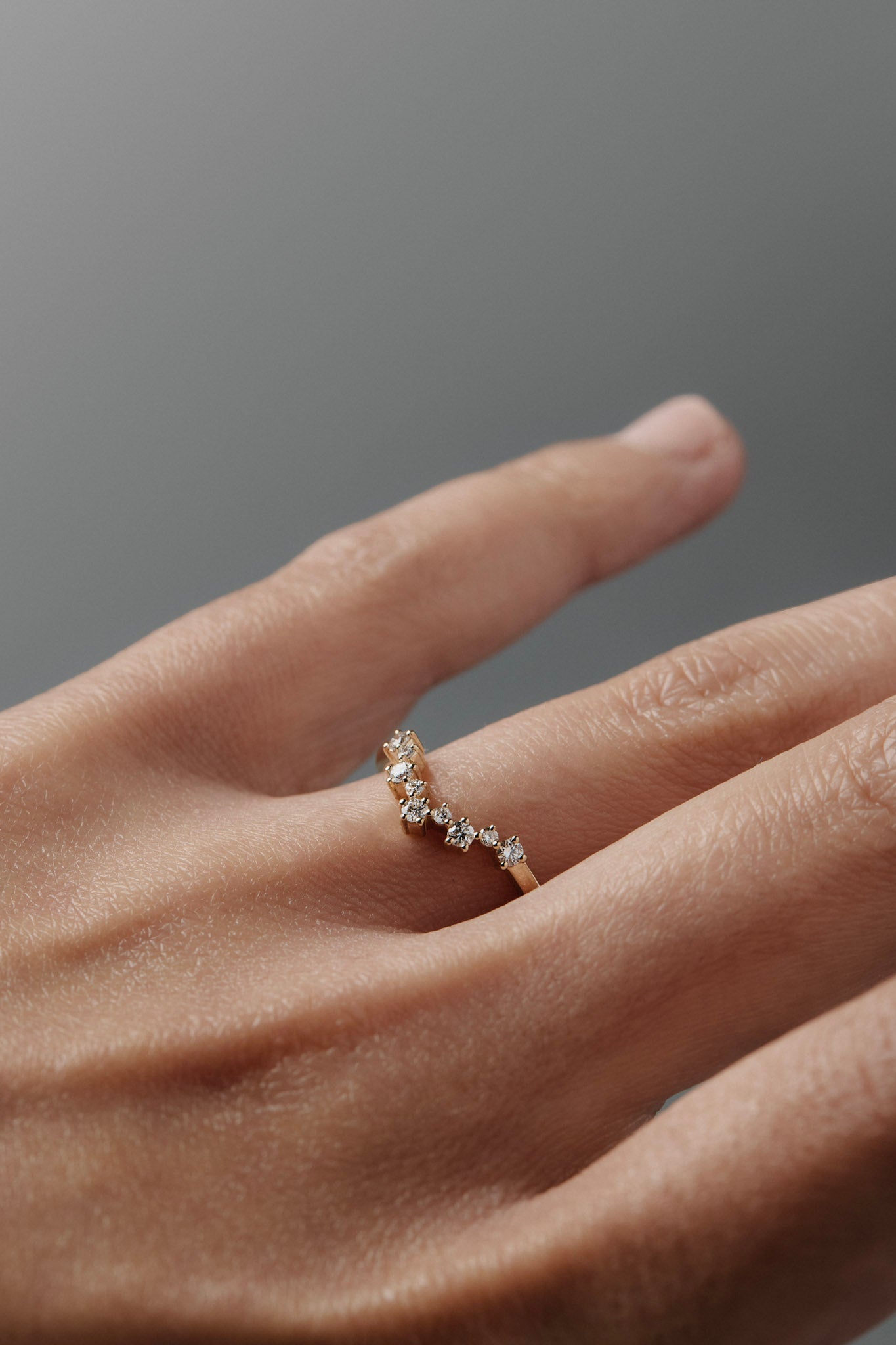 Close-up of a woman's hand wearing the Snowflake curved diamond wedding band, featuring delicate diamonds in a snowflake inspired design. 