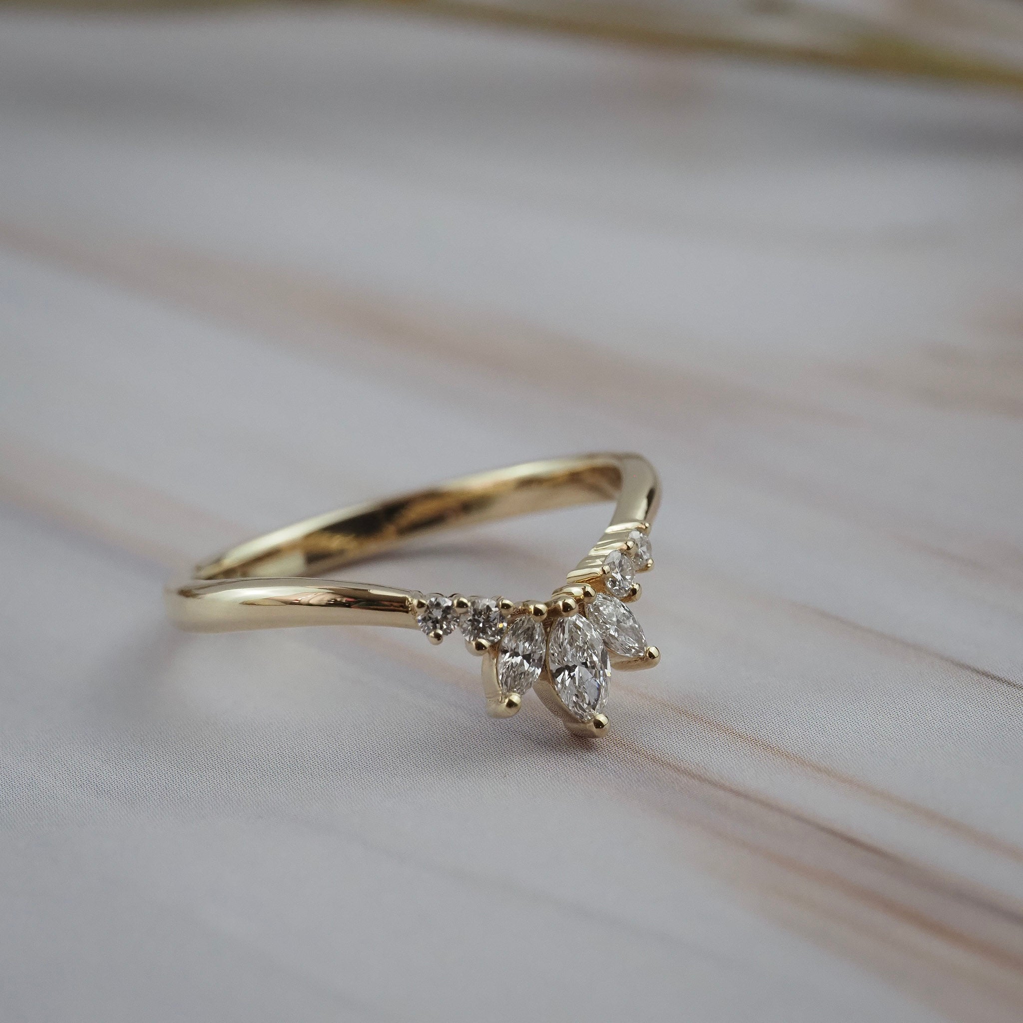 Side profile of the Trillium curved gold wedding band featuring marquise and round diamonds in a floral-inspired design.