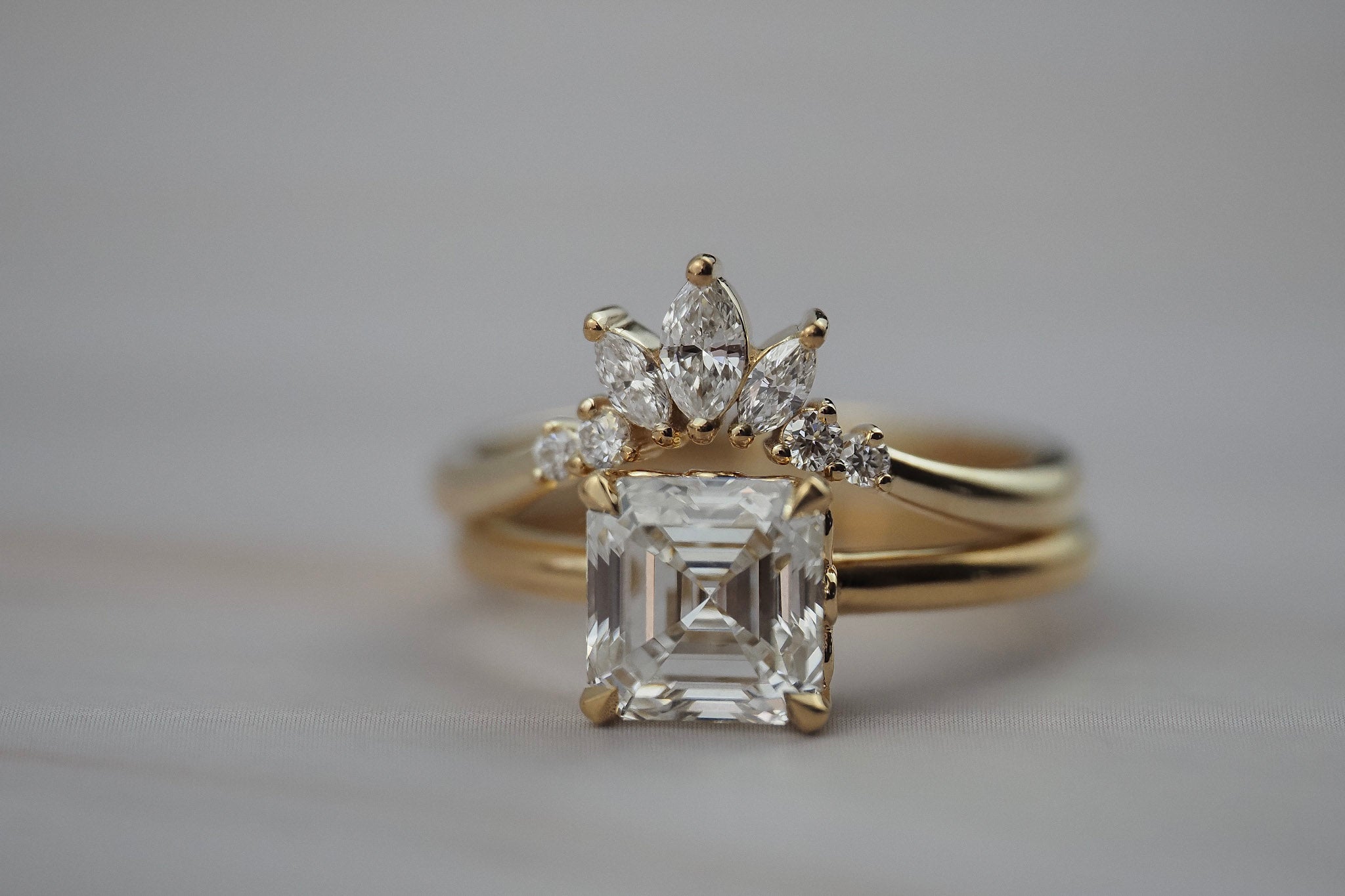 Trillium curved gold wedding band paired with an asscher-cut diamond engagement ring.