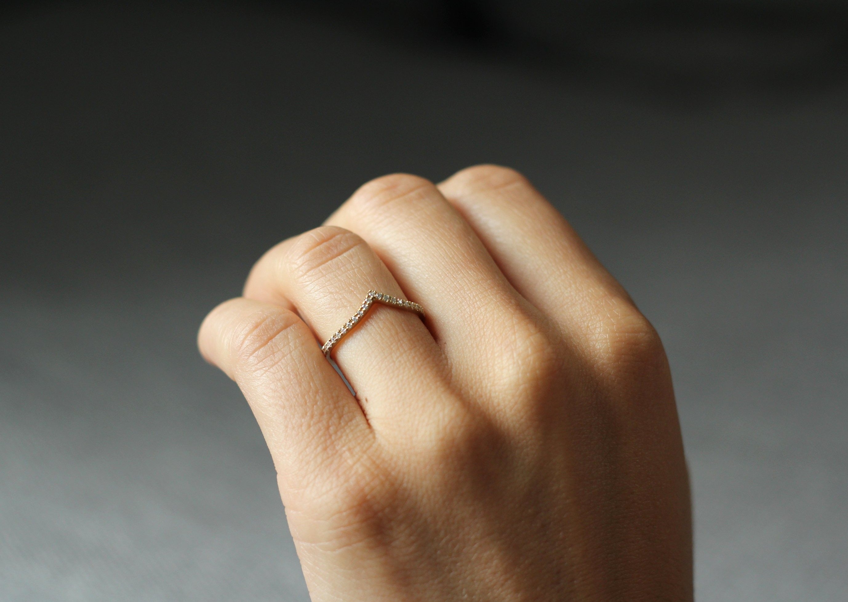 Close up of model hand wearing the Chevron Mia womens wedding band by Fluid Jewellery in yellow gold