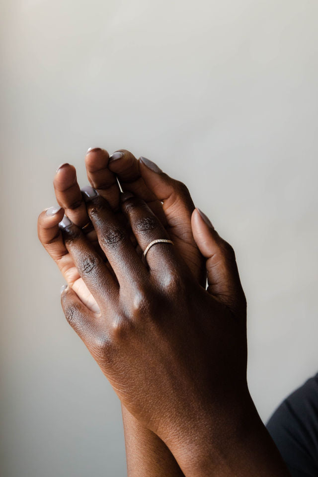 Close up of model hand wearing the curved Caia womens wedding band by Fluid Jewellery in yellow gold 2