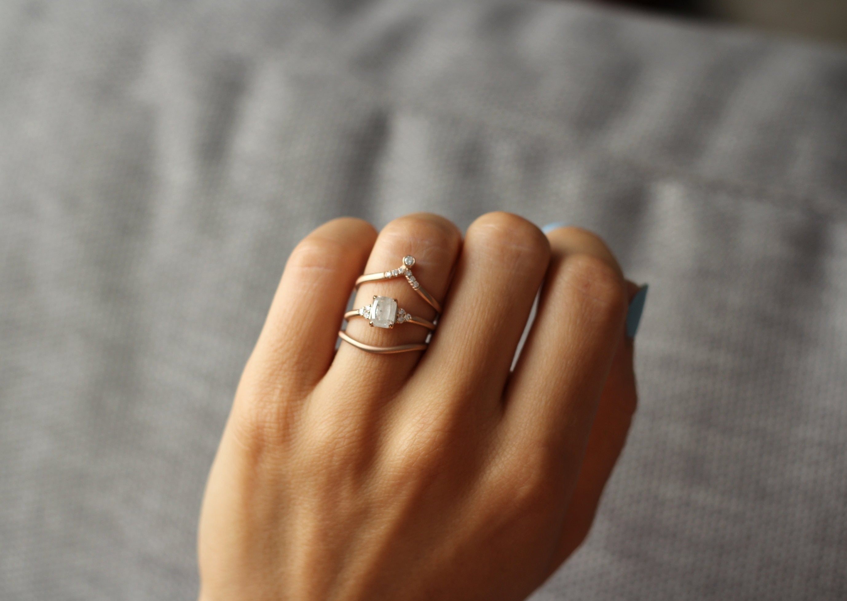 Close up of model hand wearing the curved flow womens wedding band by Fluid Jewellery in rose gold