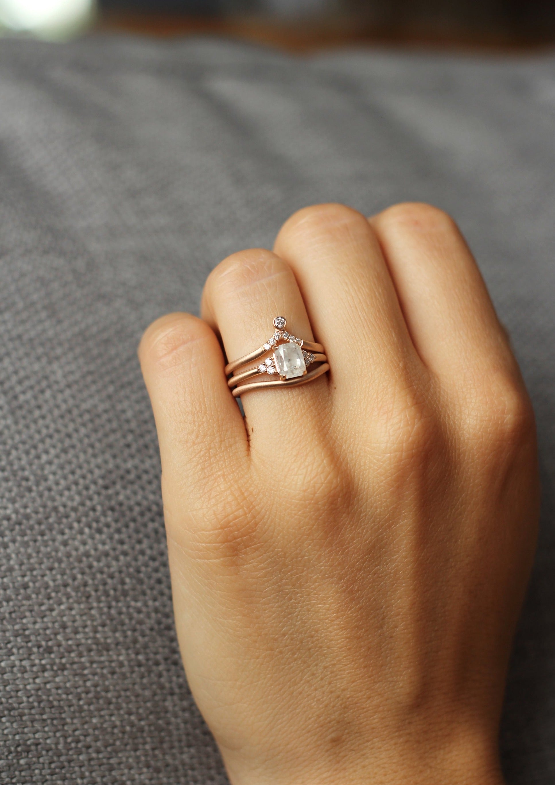 Close up of model hand wearing the curved flow womens wedding band by Fluid Jewellery in rose gold