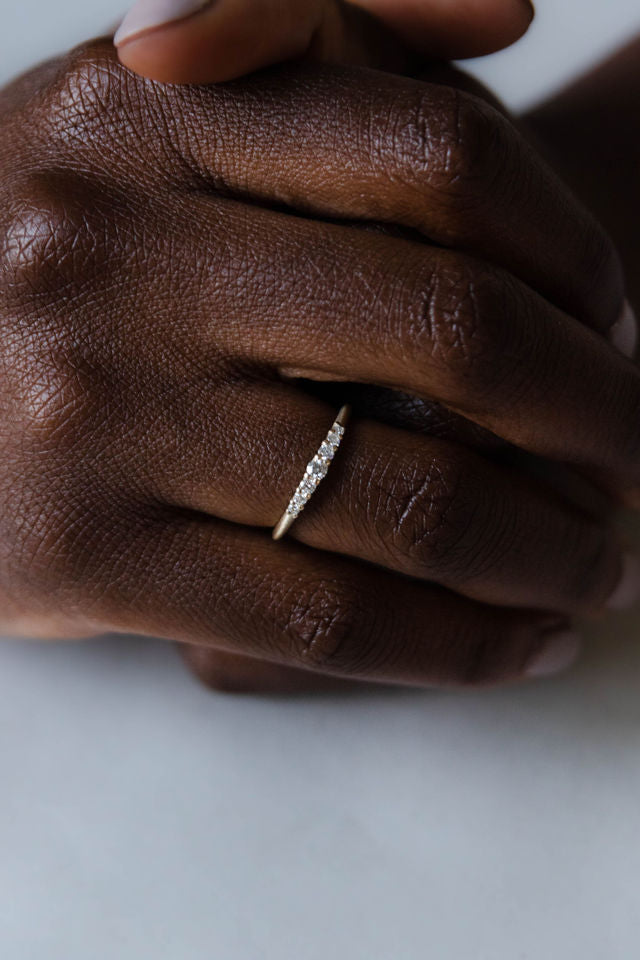 Close up of  model hand wearing the seven stone Elsie womens wedding band by Fluid Jewellery in yellow gold